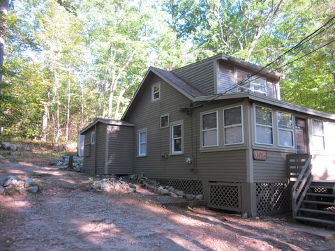 Gray cottage with screened porch among trees