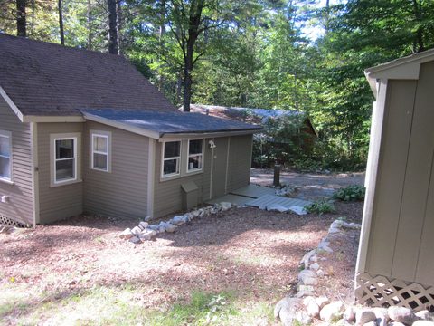 Side of the cottage with a gravel parking area